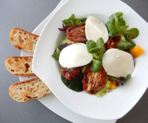 Salát s mozarellou, sušenými rajčaty a bagetkou na česnekovém másle